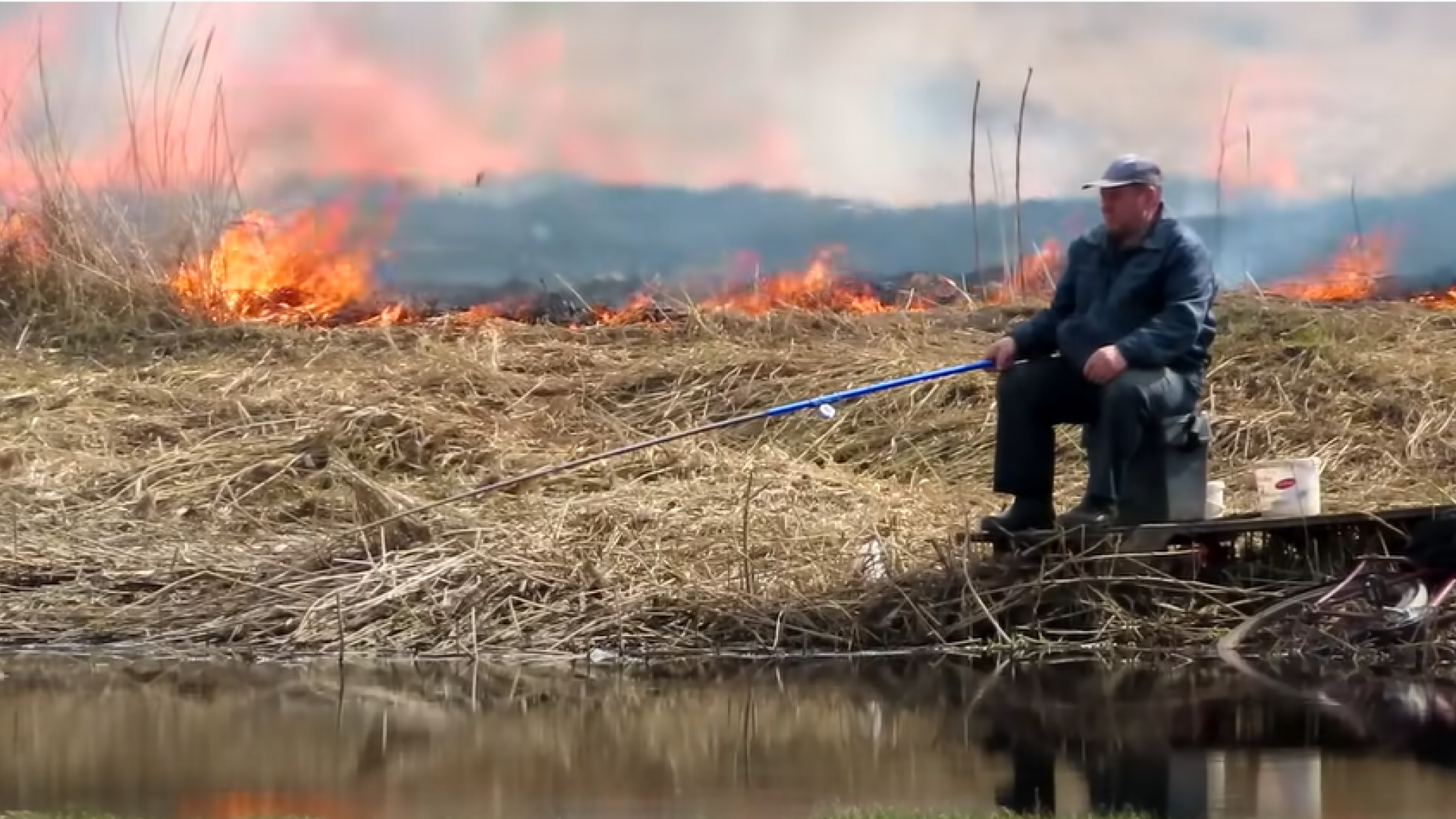 Un bărbat pescuia liniștit în timp ce câmpul ardea în spatele lui. ”Nu e nimic nou aici”