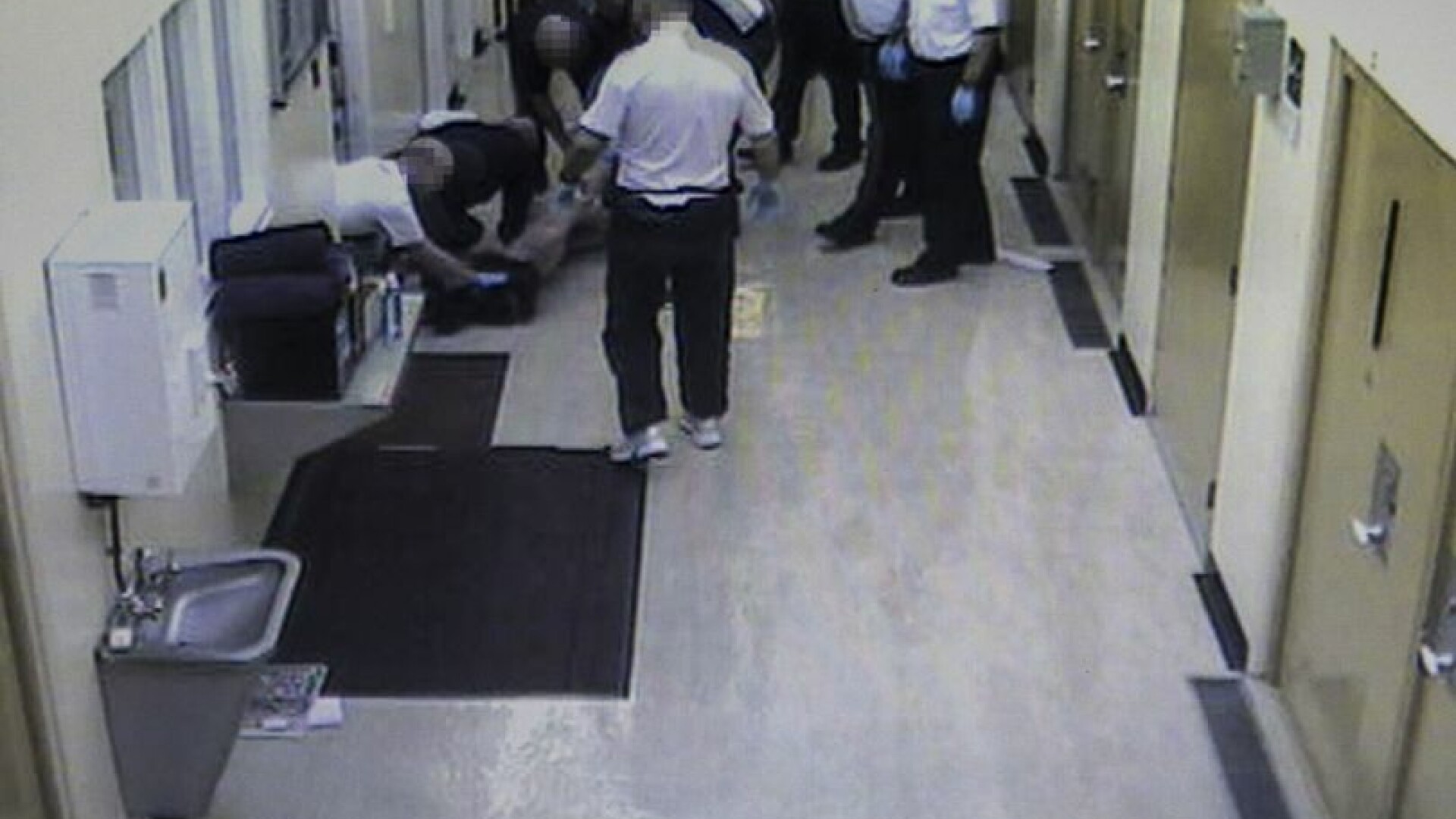 Gardienii se bucură în timp ce un deținut bătut este transportat la spital