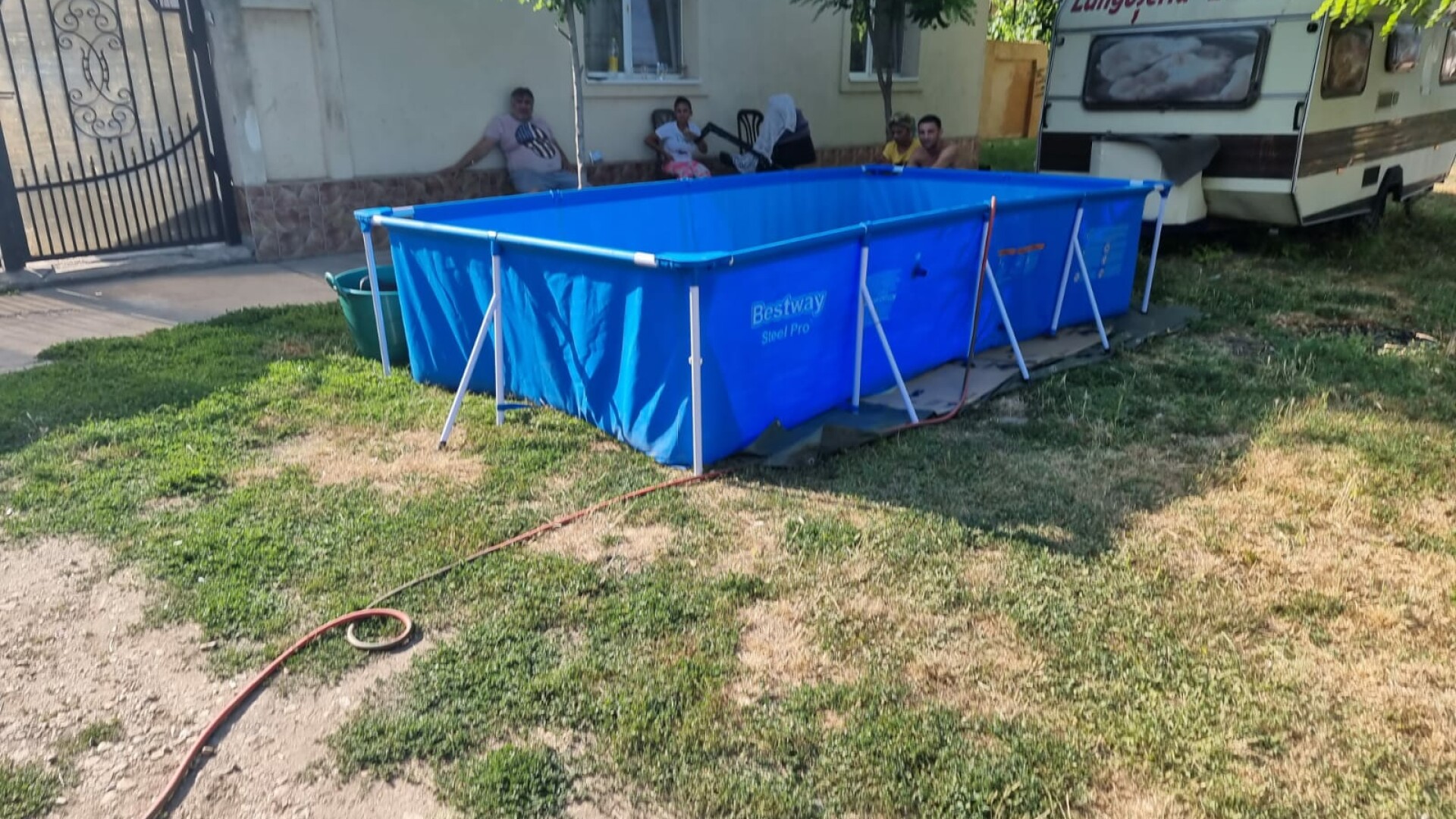 O familie din Timiș și-a făcut piscină în fața casei cu apă adusă de la 50 de metri cu furtunul, de la fântâna publică
