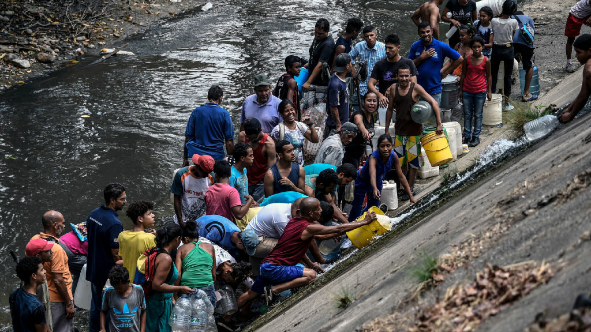 Venezuelenii adună apă dintr-un canal. Pana masivă de curent se prelungește