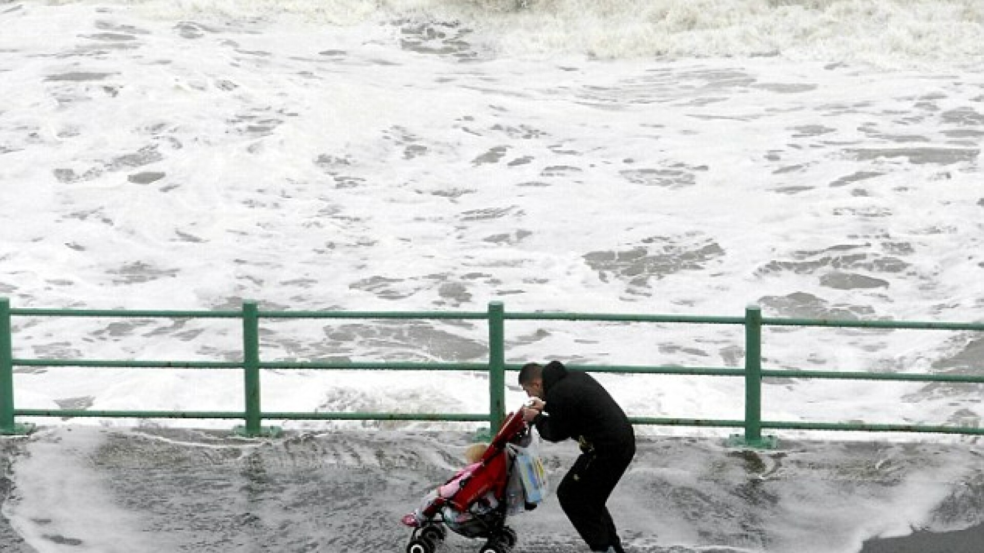 un tata isi plimba copilul la malul marii, in timpul furtunii