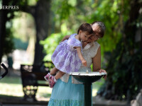 canicula, O fetita ajutata de bunica ei se spala pe maini la o cismea din parcul Cismigiu din Bucuresti.