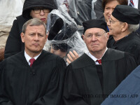Supreme Court Justice Stephen Bryer(L) assists Justice Ruth Bader Ginsburg(2nd-L) with a rain poncho during inauguration ceremonies for President-elect Donald Trump