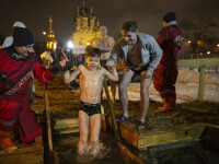 Un băiat este ajutat să facă o baie în apă înghețată, de Bobotează, în Moscova