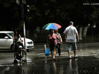 Trecatori surprinsi de ploaie in cartierul Militari din Capitala.