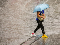 o femeie merge cu umbrela pe vreme ploioasa
