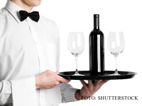 chelner cu sticla de vin si pahare pe tava