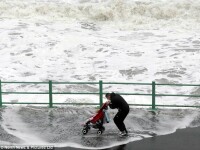 un tata isi plimba copilul la malul marii, in timpul furtunii