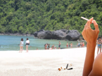 turista care fumeaza pe plaja