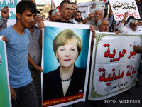 refugiati purtand o pancarta cu portretul lui Merkel