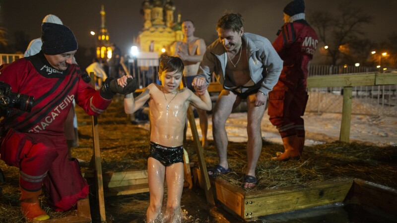 Un băiat este ajutat să facă o baie în apă înghețată, de Bobotează, în Moscova