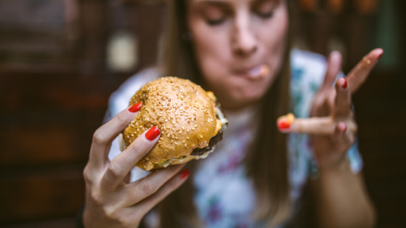femeie care mananca un burger