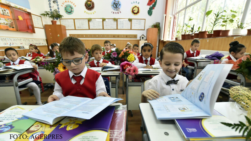 Mai multi copii din clasa 1C a Scolii Gimnaziale 'Aurel Vlaicu' din Fetesti, judetul Ialomita, rasfoiesc manualele primite cu ocazia inceperii anului scolar preuniversitar 2016-2017.