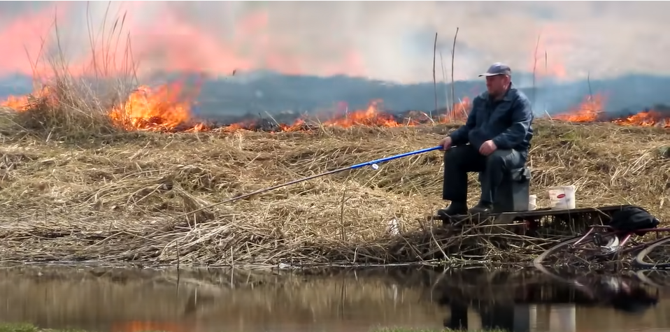 Un bărbat pescuia liniștit în timp ce câmpul ardea în spatele lui. ”Nu e nimic nou aici” VIDEO