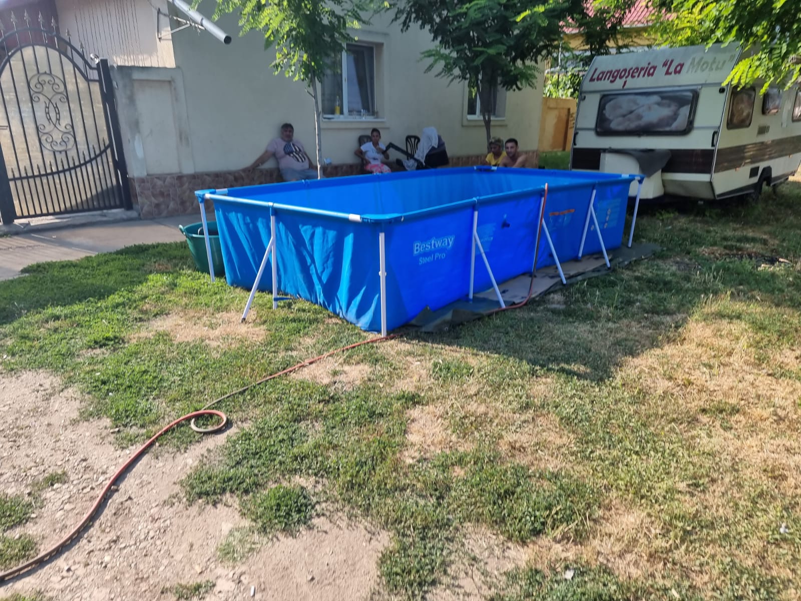 O familie din Timiș și-a făcut piscină în fața casei cu apă adusă de la 50 de metri cu furtunul, de la fântâna publică