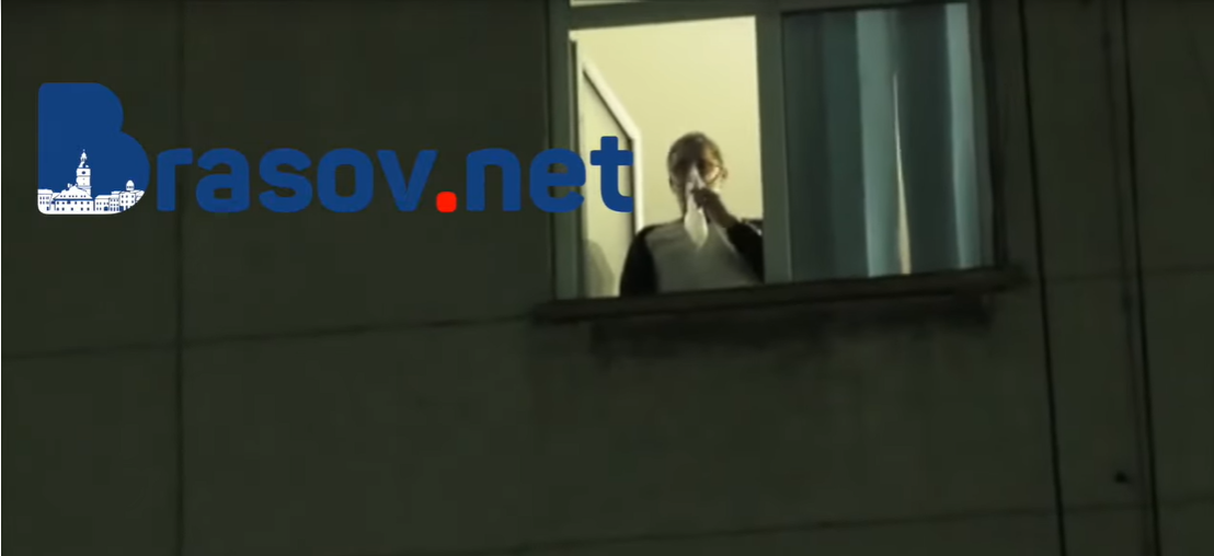 Un bolnav de Covid cu masca de oxigen pe față privește de la geamul spitalului manifestanții anti-restricții
