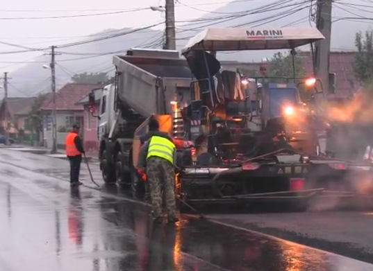 Asfaltare pe ploaie in orasul Dej. Motivul pentru care muncitorii au turnat tone de asfalt pe o strada cu balti. VIDEO
